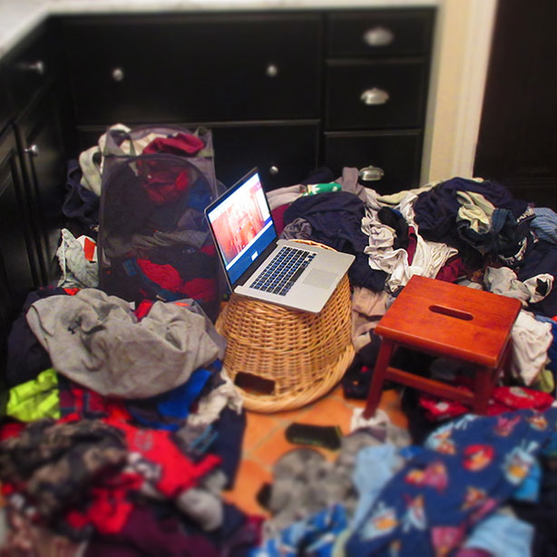 computer surrounded by piles of laundry